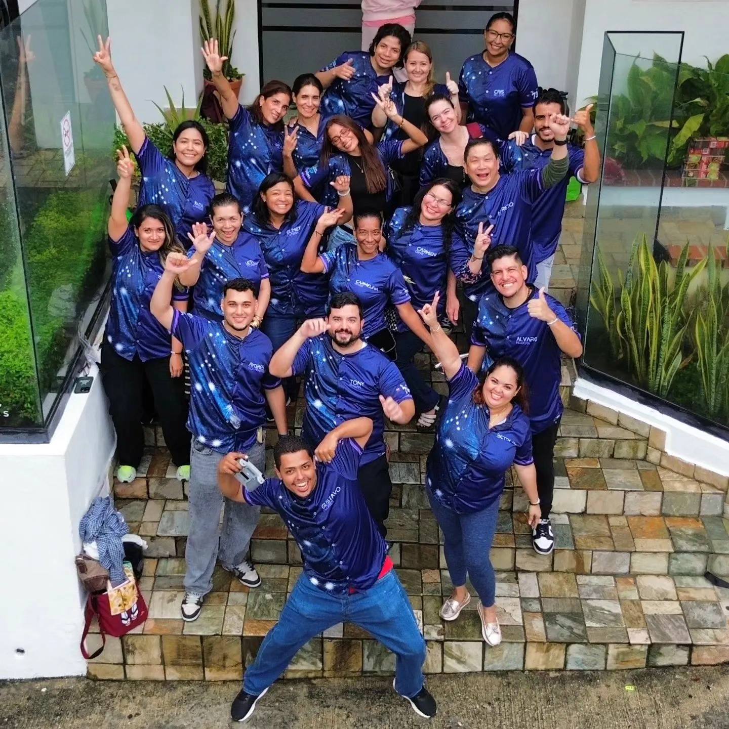 Graduados GOL con camisetas azules posando en escaleras